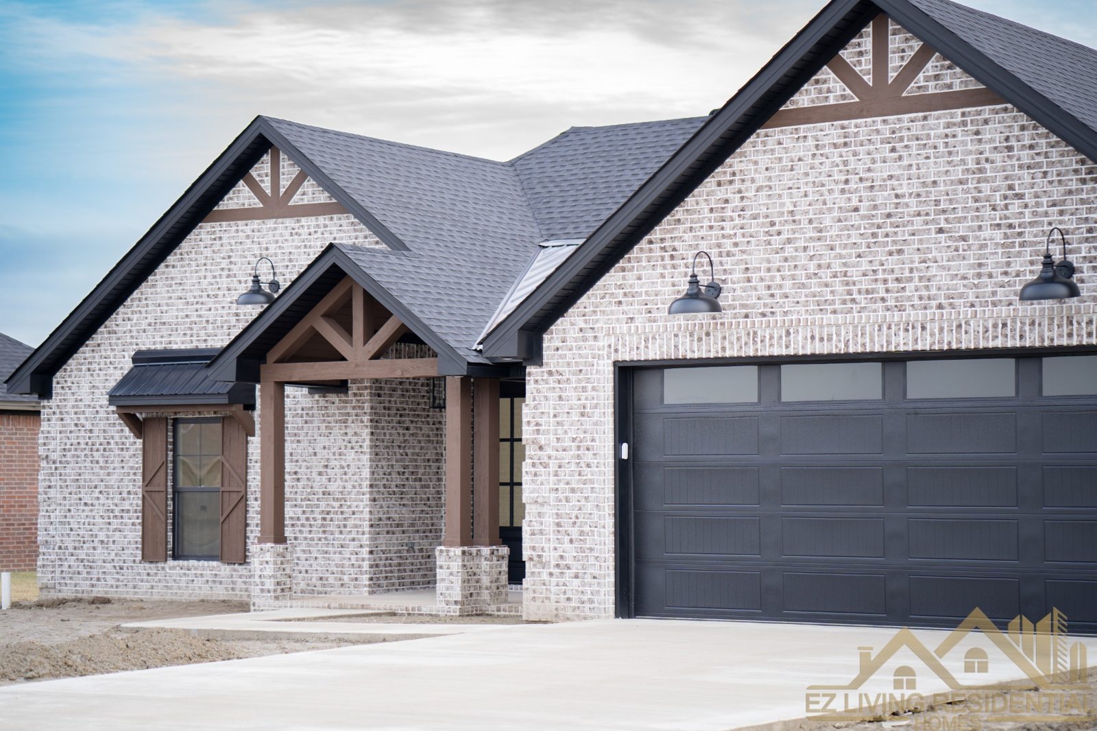 Finished white brick home with dark garage door and timber porch