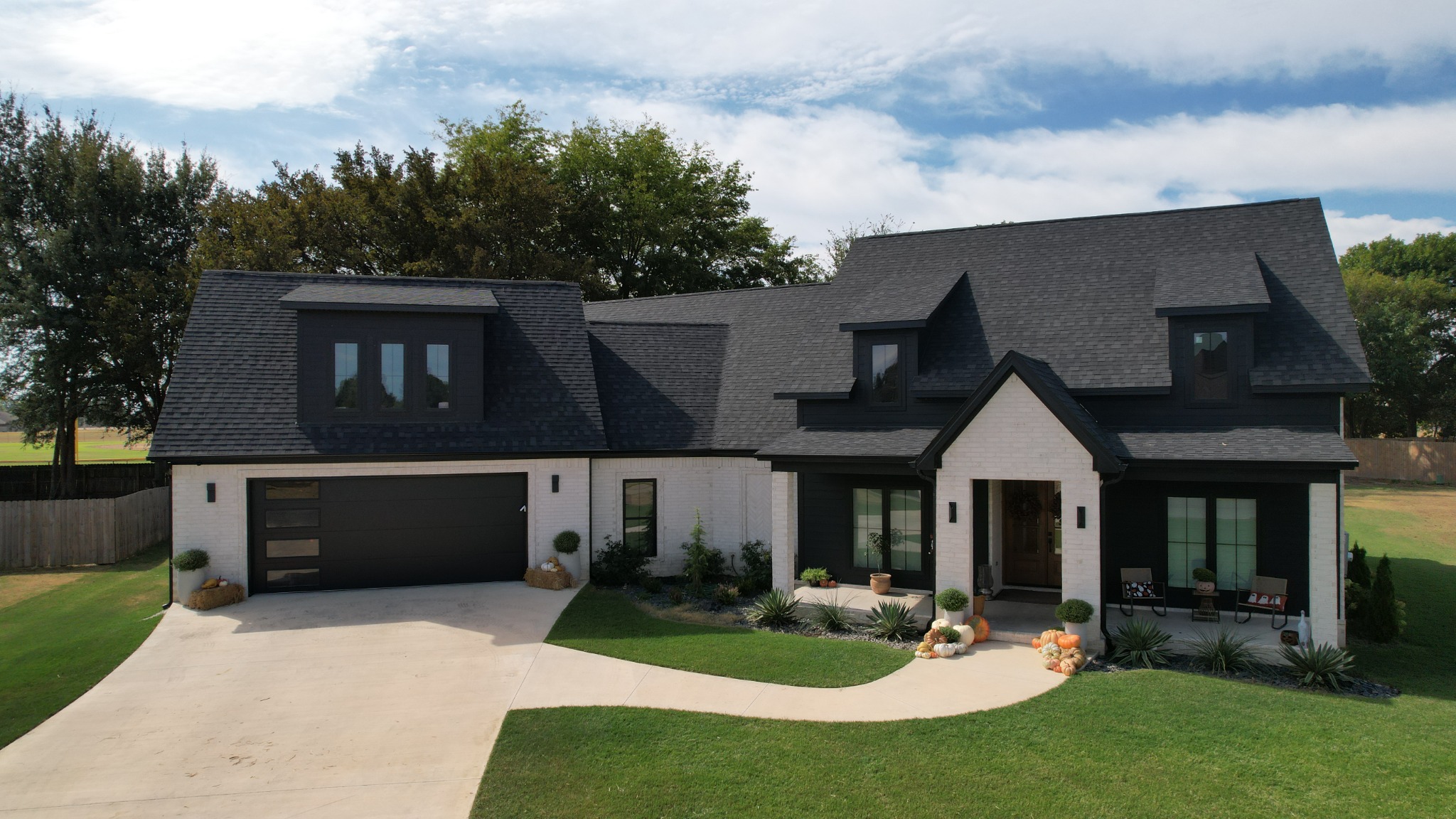 Completed Sicily Circle home from above, with white brick, dark siding, and a black two-car garage door