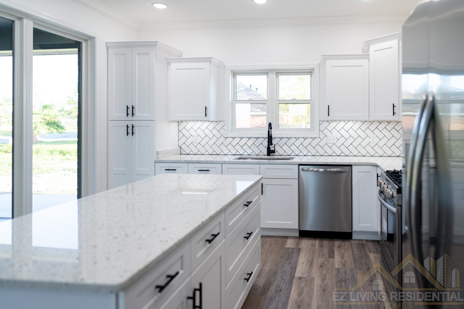 White kitchen with large island and herringbone backsplash