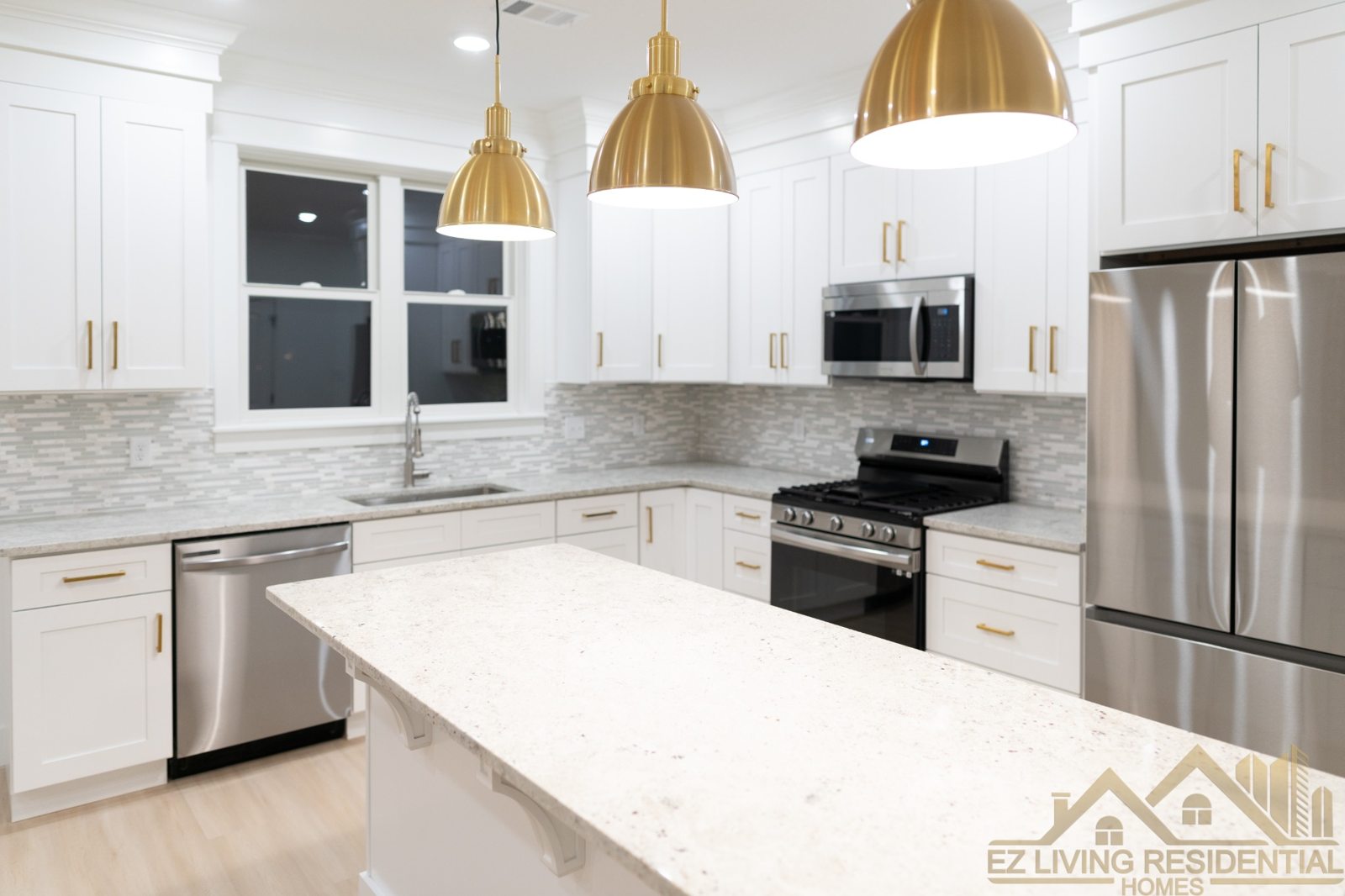 White kitchen with island and brass pendants